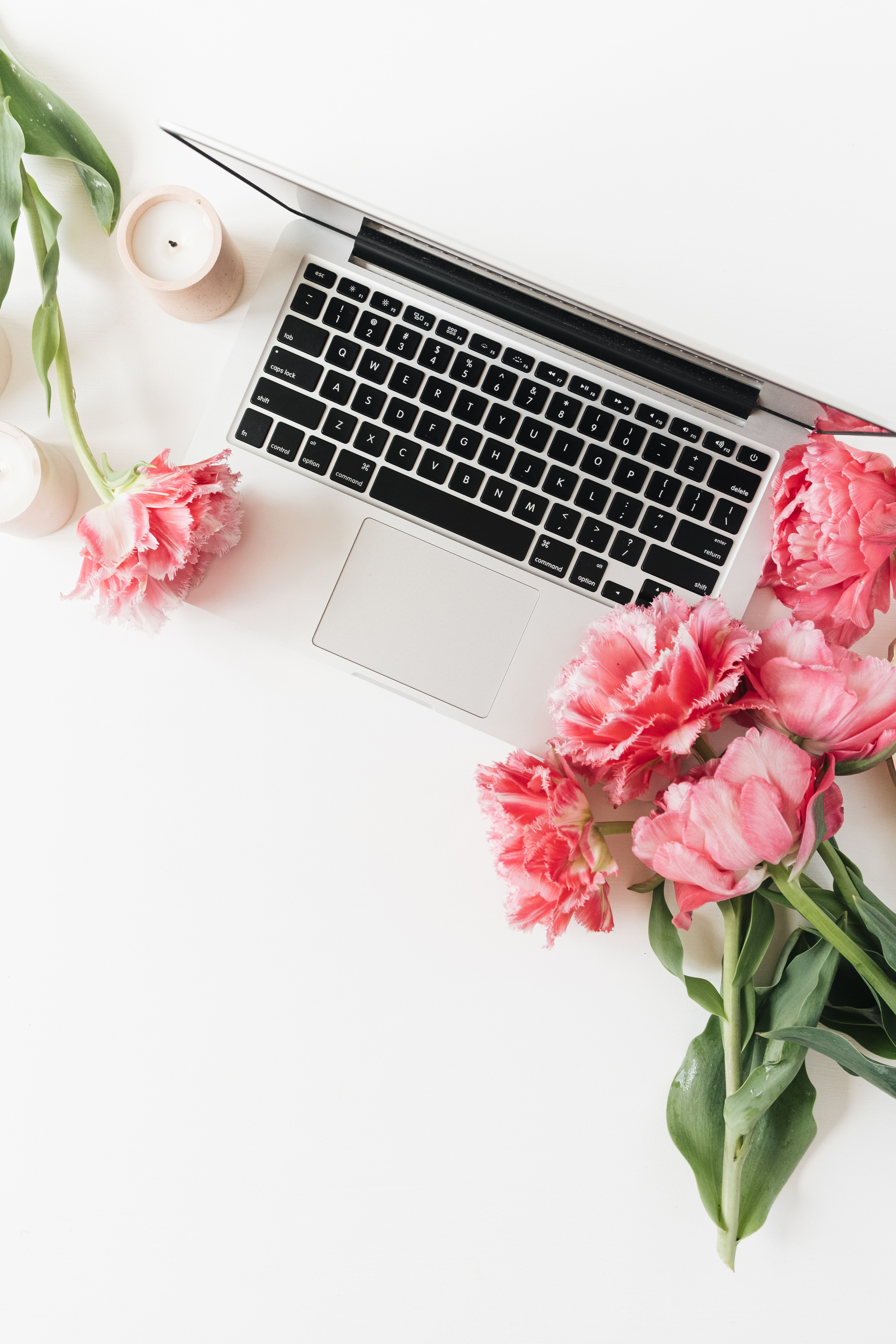 Laptop Computer with Pink Flowers and Candle on Table 